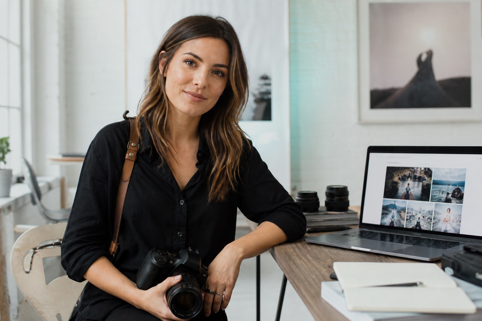 Fotografin an einem hellen Studio-Schreibtisch mit Kamera und Laptop mit Portfolio-Website